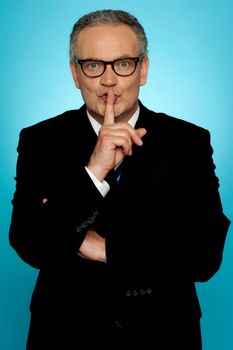 Silence please, businessman looking at you with finger on his lips