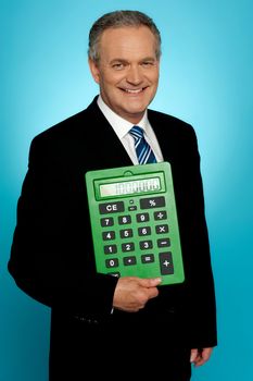 Senior executive posing with big green calculator, showing it to camera