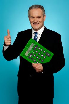 Businessman showing thumbs up, holding calculator. All on gradient blue background