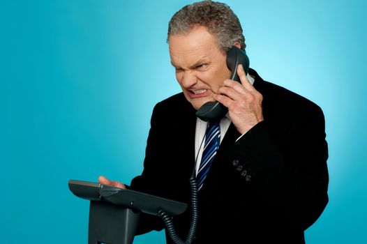 Irritated businessman communicating on phone. Anger expression on his face