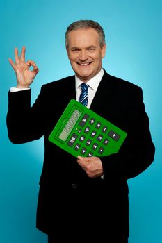 Confident executive holding calculator and gesturing okay sign isolated over gradient background