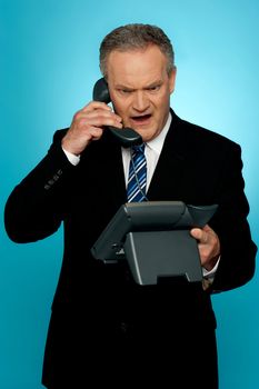 Angry aged corporate man yelling on phone isolated against gradient background