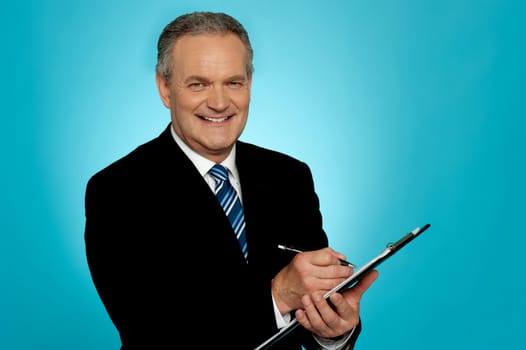 Attractive senior man writing on clipboard. All on gradient blue background