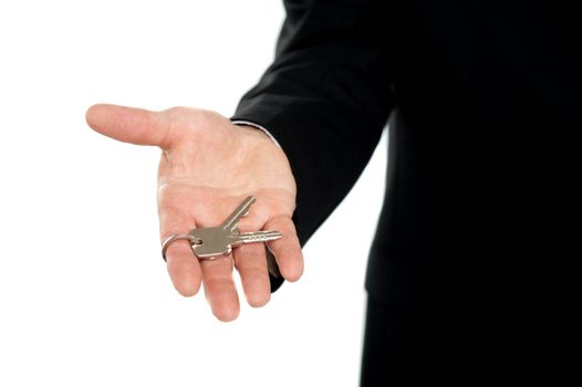 Businessman offering keys, closeup shot. Isolated over white background