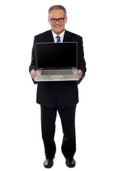 Aged businessman showing newly launched laptop, full length shot