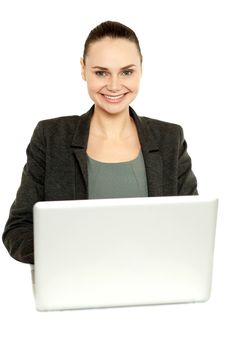 Attractive corporate female working on laptop and smiling at camera