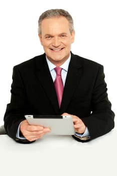Handsome aged business male using tablet pc, smiling at camera