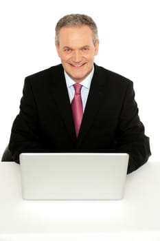Portrait of successful senior businessman sitting with laptop in front of him