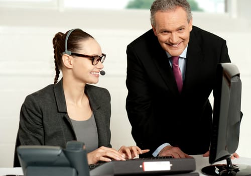 Successful business team working together. Woman typing on keyboard and aged man looking at you