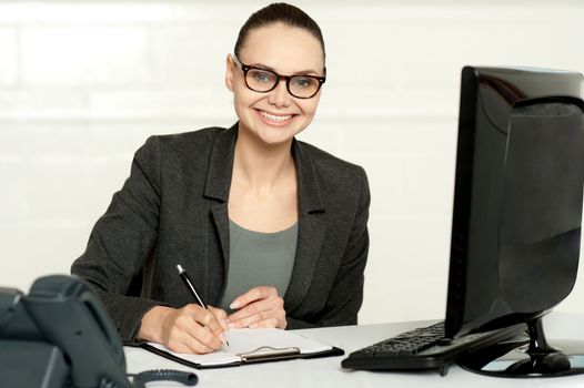 Female executive writing on notepad isolated in office