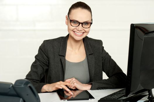 Pretty manager working on wireless tablet device sitting in her office