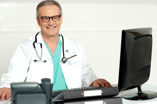 Aged physician with stethoscope around his neck looking at camera
