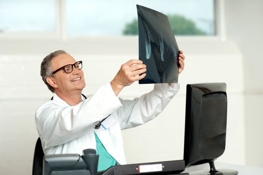 Senior surgeon in glasses looking at x-ray report of a patient