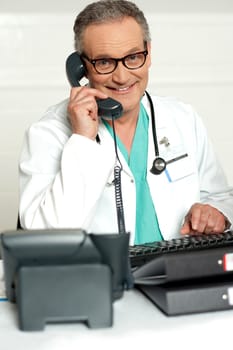 Happy aged medical expert taking on phone wearing glasses