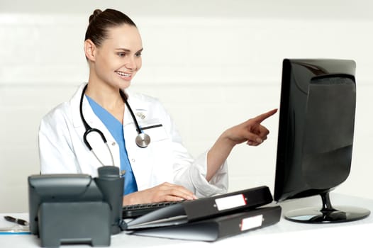 Female medical expert pointing at computer screen sitting in her lab
