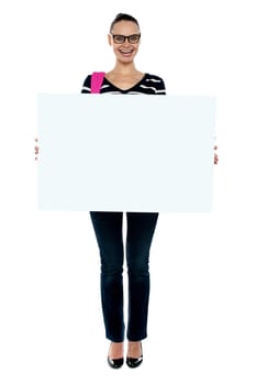Full length shot of college girl holding white ad board and smiling at camera