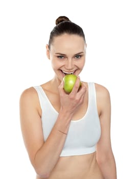 Cheerful healthy fit woman eating fresh green apple isolated over white