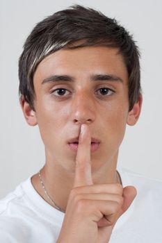 young swarthy man showing silence gesture, hand over mouth