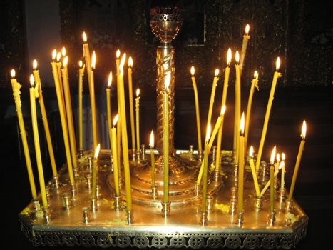 Bright burning church candles on candlesticks in church