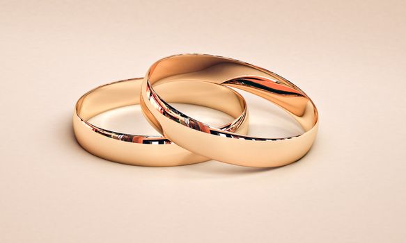 Wedding rings on a light background with reflections.
