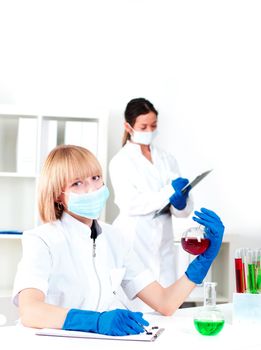 portrait of a chemist in protective mask, holding a test tube with red liquid