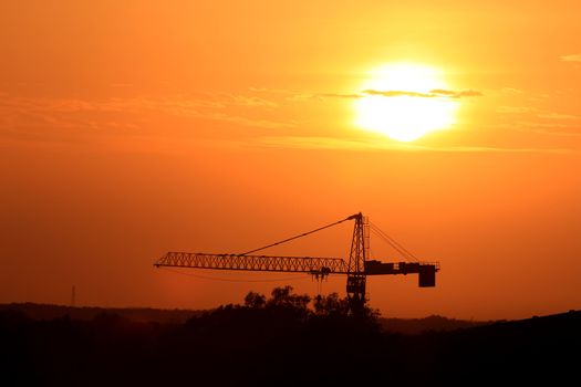 Industrial landscape with silhouettes of cranes on the sunset background