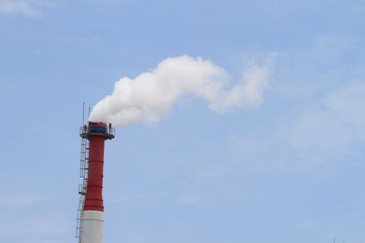 Plant pipe with smoke against blue sky