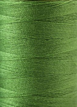 Macro view of green thread wound on a spool