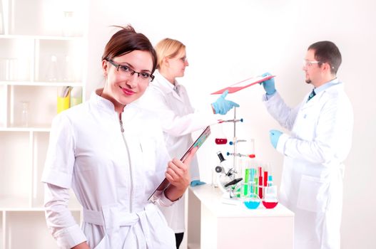 Portrait of a doctor with a clipboard, in the background work colleagues