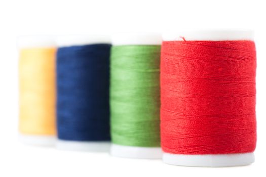 Four spools with green, red, blue and yellow threads