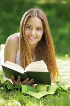Closeup of a beautiful young woman reading book at park