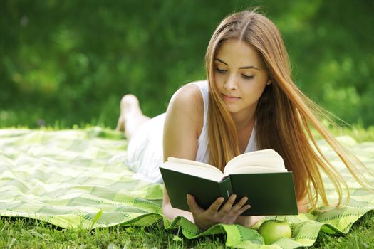 Closeup of a beautiful young woman reading book at park