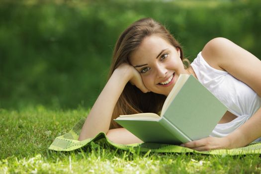 Closeup of a beautiful young woman reading book at park
