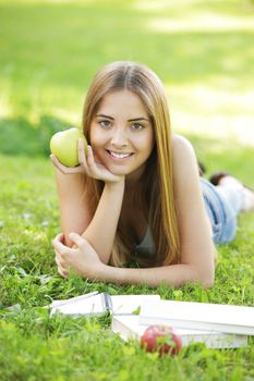 Young smiling woman outdoors holding an apple