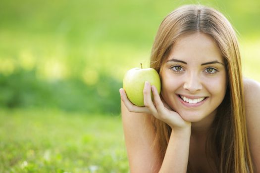 Young smiling woman outdoors holding an apple