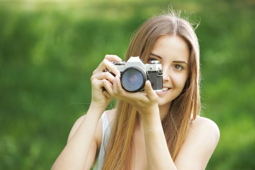 Portrait of beautiful smiling blonde girl , making photos at summer green park.