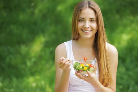 Portrait of happy beautiful young woman eating vegetable salad