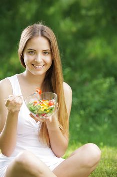 Portrait of young happy woman eating salad