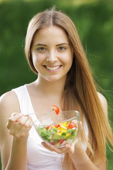 Portrait of young happy woman eating salad