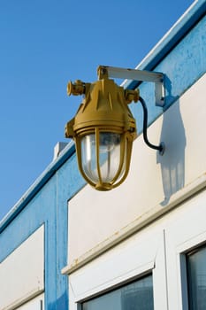 Explosion proof lighting with a heavy protective metal casing mounted on the exterior wall of a building