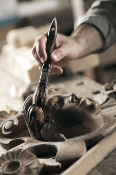 Close Up of carpenter apply varnish to a wooden sculpture