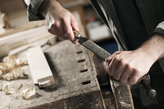 Carpenter working on a piece of wood with a file