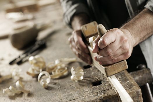 Hands of a carpenter planed wood, workplace