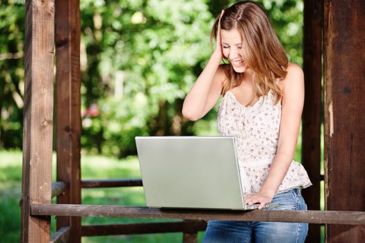 Pretty woman with laptop on summer day outdoor