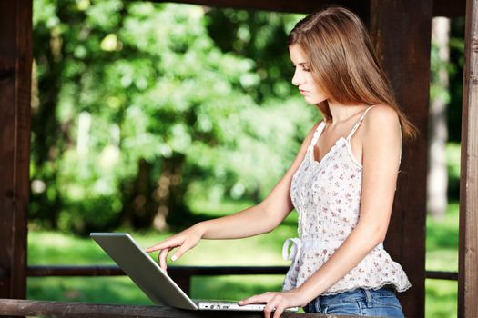 Pretty woman with laptop on summer day outdoor