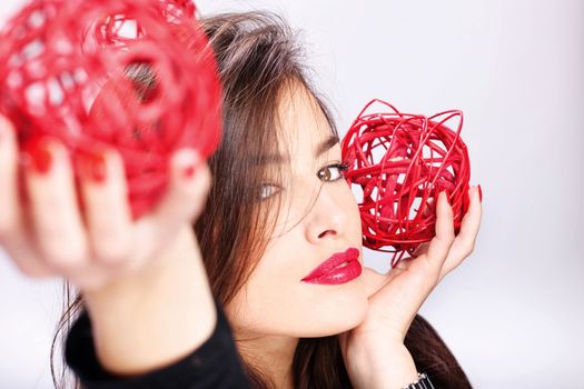 Pretty brunette woman holding two red balls