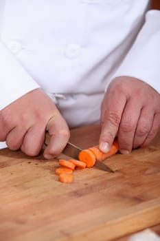 Male chef chopping carrot