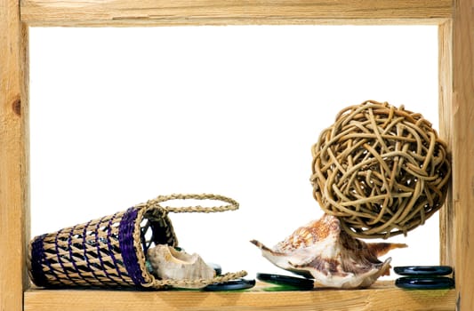 Wicker, green pieces of glass and sea shells inside rough wooden frame on white background