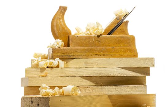 Wooden plane, boards and planed wood shavings on a white background