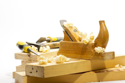 Wooden plane, boards and planed wood shavings on a white background